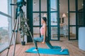 Smiling fitness blogger filming video doing sit ups with barbells