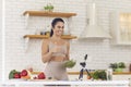 Smiling fit vlogger filming culinary video blog, giving dieting advice and sharing salad recipe