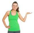 Smiling fitness young woman presenting something on empty palm