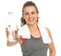 Smiling fitness young woman with towel giving bottle of water Royalty Free Stock Photo