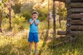A smiling five-year-old boy in blue clothes stands tall in the Park on a natural background in the summer in the contra sunset