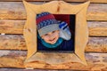 Smiling five-year-old boy boy looks out the window of the house. children`s wooden house on the Playground