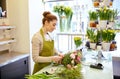 Smiling florist woman making bunch at flower shop