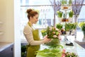 Smiling florist woman making bunch at flower shop