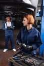 Smiling forewoman in gloves holding wrench