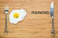 Smiling fried egg lying on a wooden cutting board with morning inscription near it. Classic Breakfast concept. Royalty Free Stock Photo