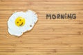 Smiling fried egg lying on a wooden cutting board with morning inscription near it. Classic Breakfast concept.