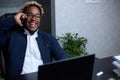 Smiling friendly African man talking on phone in office Royalty Free Stock Photo