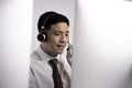 Asian call centre operator wearing headset with microphone sitting with computer and talking with customer in customer service Royalty Free Stock Photo