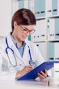 Smiling friendly doctor writing notes Royalty Free Stock Photo