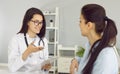 Smiling friendly female doctor discusses diagnosis with woman and makes notes in clipboard. Royalty Free Stock Photo