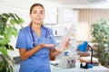 Friendly female doctor with papers explaining treatment procedure in office Royalty Free Stock Photo