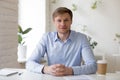 Smiling friendly millennial businessman sitting at workplace