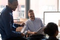 Smiling friendly multiethnic coworkers group talking laughing in office