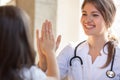 Smiling friendly pediatrician doctor giving five to little girl patient Royalty Free Stock Photo