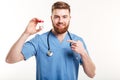 Smiling friendly pharmacist pointing finger at bottle with tablets Royalty Free Stock Photo