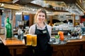 Smiling friendly waitress serving a pint of draft beer in a pub. Portrait of happy young woman serving beer in bar Royalty Free Stock Photo