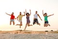 Smiling friends dancing and jumping on beach