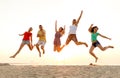Smiling friends dancing and jumping on beach Royalty Free Stock Photo