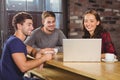 Smiling friends having coffee together and looking at laptop Royalty Free Stock Photo