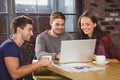 Smiling friends having coffee together and looking at laptop Royalty Free Stock Photo