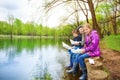 Smiling friends hold paper boats near river