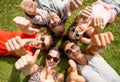 Smiling friends showing thumbs up lying on grass Royalty Free Stock Photo