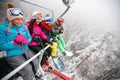 Friends skiers on ski lift ride up on ski slope at snowy day