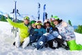 Smiling friends after skiing sit on snow together