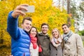 Smiling friends with smartphone in city park