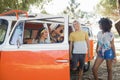 Smiling friends standing by camper van at campsite