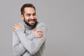 Smiling frozen young man in gray sweater posing isolated on grey background, studio portrait. Healthy fashion lifestyle