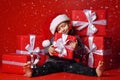 Smiling funny child in Santa red hat holding Christmas gift in hand. Christmas concept. Royalty Free Stock Photo