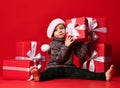 Smiling funny child in Santa red hat holding Christmas gift in hand. Christmas concept.