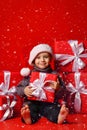 Smiling funny child in Santa red hat holding Christmas gift in hand. Christmas concept.