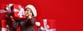 Smiling funny child in Santa red hat holding Christmas gift in hand. Christmas concept.