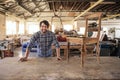 Smiling furniture maker sanding a chair on his workbench Royalty Free Stock Photo