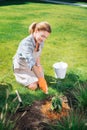 Smiling gardener enriching the soil after planting flowers in garden bed