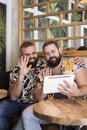 Smiling gay couple on vacation making a video call from a tablet. Concept of remote connections