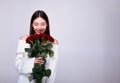 A smiling gentle young Caucasian girl holds red roses near her face