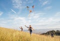 Smiling gils and brother boy with flying colorful kites - popular outdoor toy on the high grass meadow in the mountain fields.