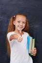 Smiling ginger girl with books and showing thumbs
