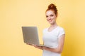 Smiling ginger woman in t-shirt holding laptop computer