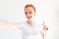 Smiling ginger woman in t-shirt making selfie and showing peace Royalty Free Stock Photo