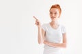 Smiling ginger woman in t-shirt pointing and looking away