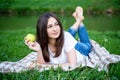 Smiling girl with an apple resting on the lawn Royalty Free Stock Photo