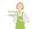 Smiling girl in apron with micro greens plant pot. Fresh sprouts and young leaves for salad. Healthy Food Sprouts Royalty Free Stock Photo