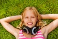 Smiling girl with arms under head wears headphones