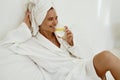 Smiling girl in bathrobe drink lemonade from glass Royalty Free Stock Photo