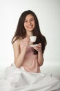 Smiling girl in the bed with a cup of coffee